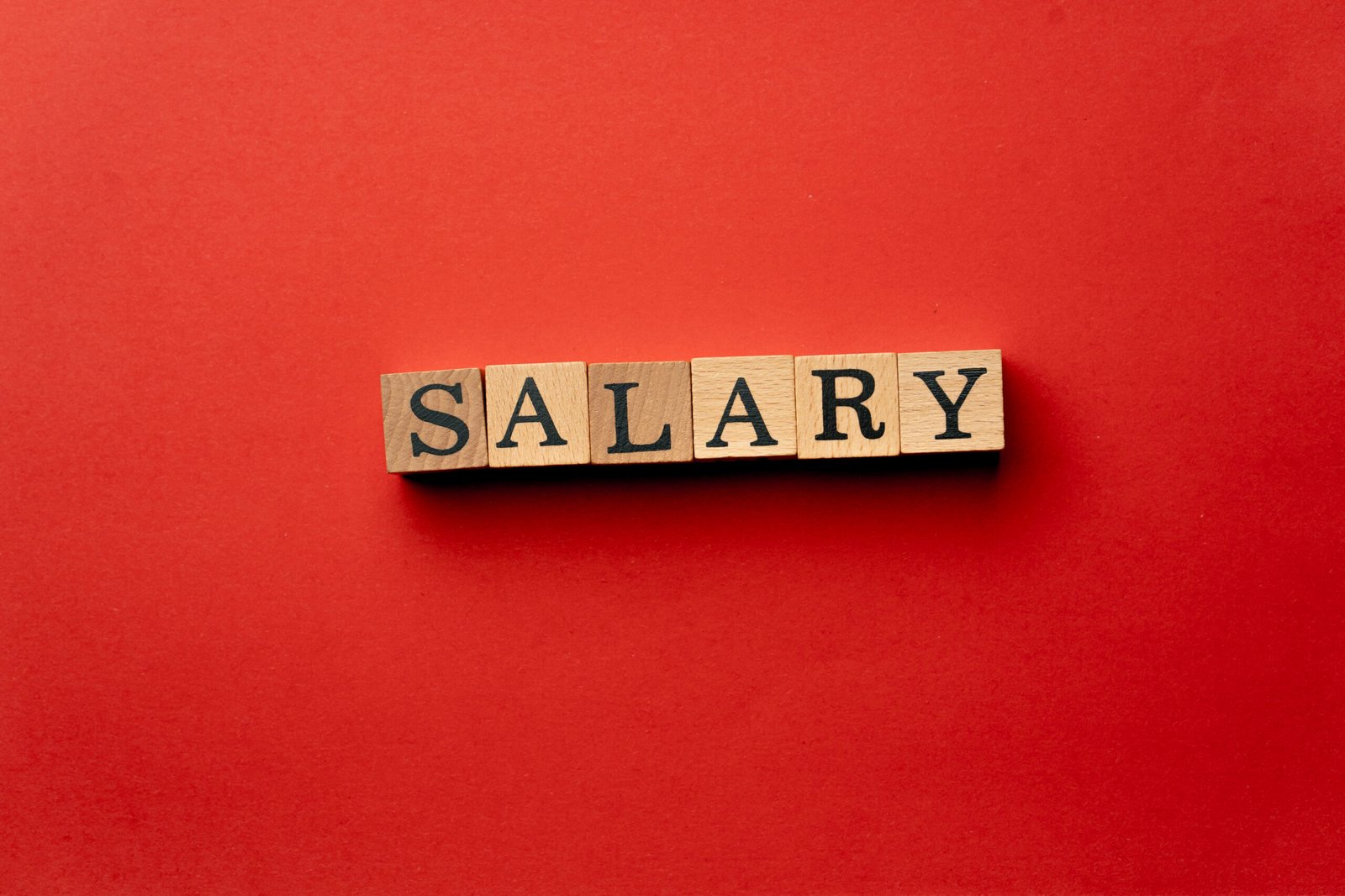 "Wooden letter blocks spelling the word salary on a red background – representing 2025 salary threshold changes for sponsored workers in the UK."