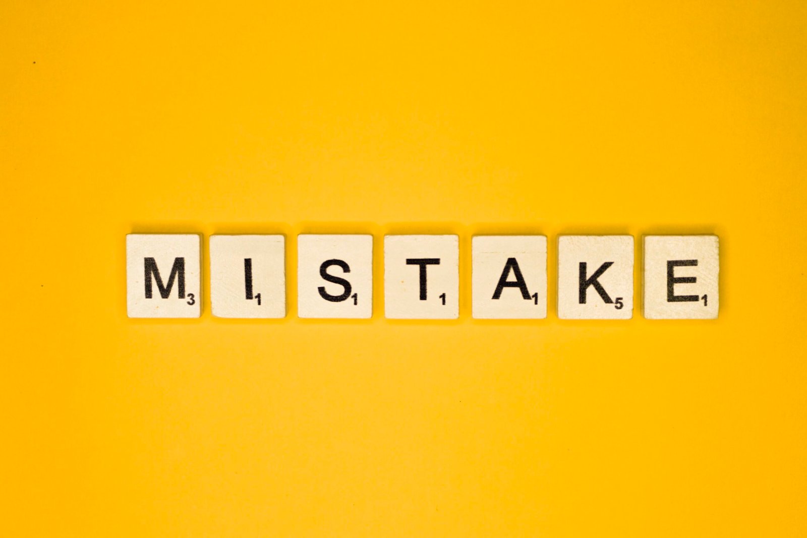 Scrabble tiles spelling the word “Mistake” on a yellow background, representing common errors in sponsor licence applications.