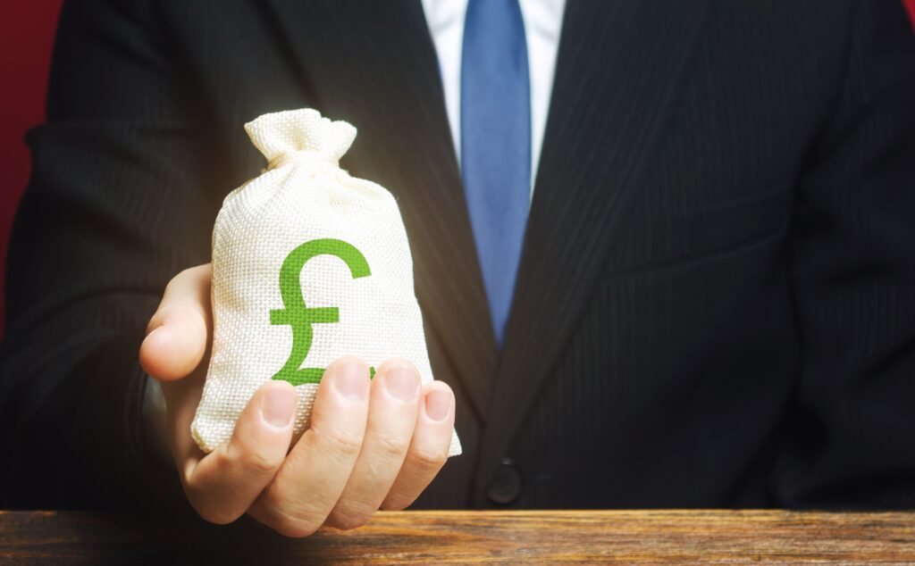Businessman holding a money bag with a pound symbol, representing UK sponsor licence fees in 2025.