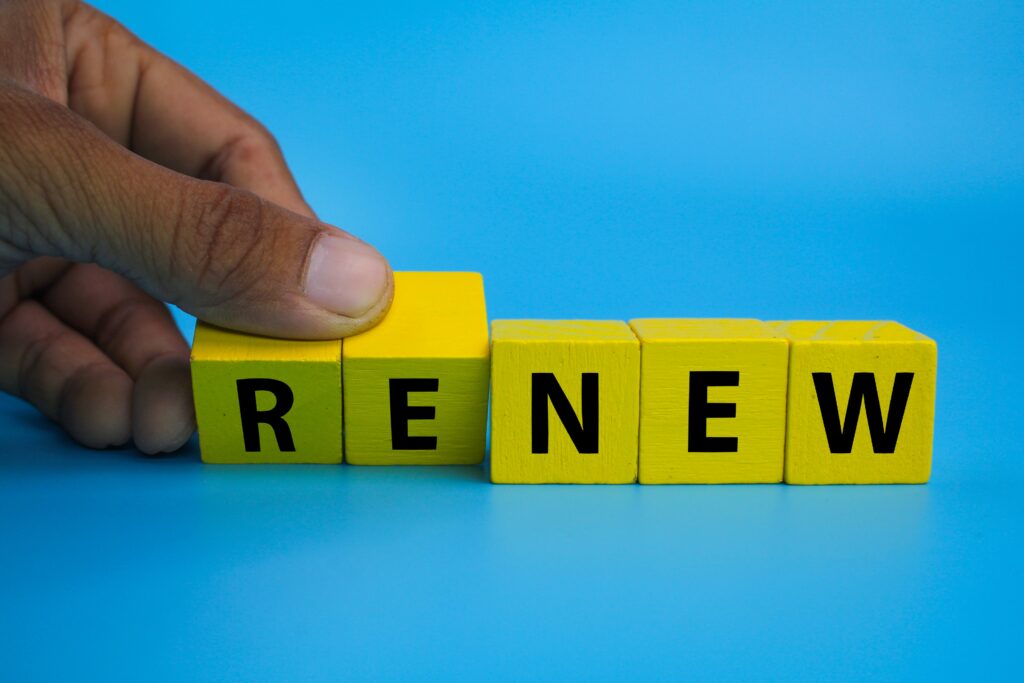 Yellow wooden blocks spelling the word "RENEW" with a hand adjusting one block, symbolising sponsor licence renewal.