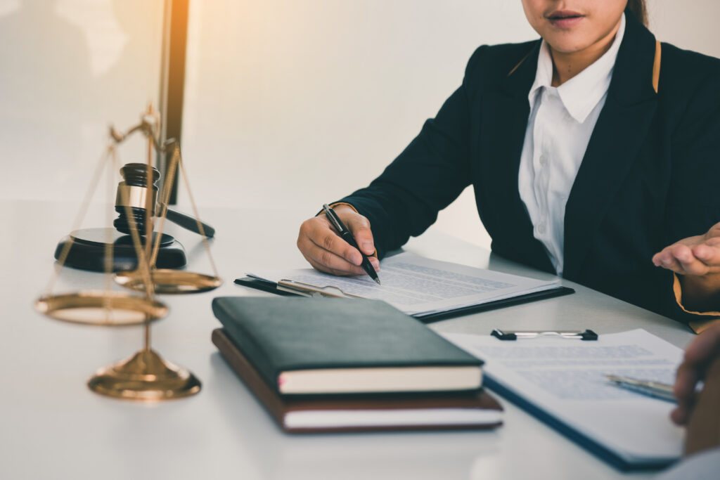 Close-up of a business professional reviewing sponsor licence application documents on a laptop, with legal books and a pen beside them, symbolising the choice between DIY applications and seeking sponsor licence legal help.