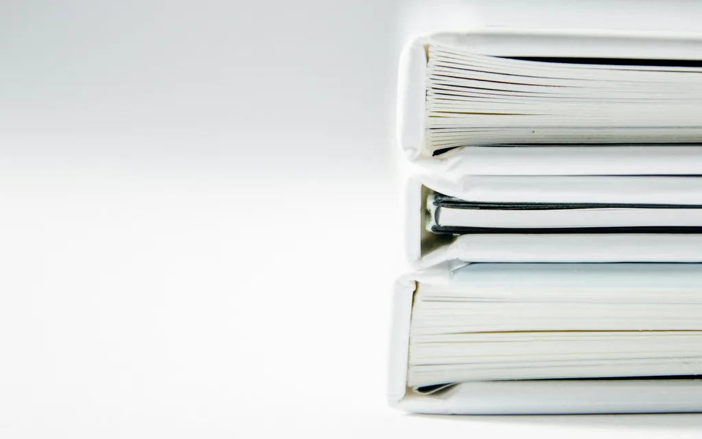 A stack of thick folders on a white surface