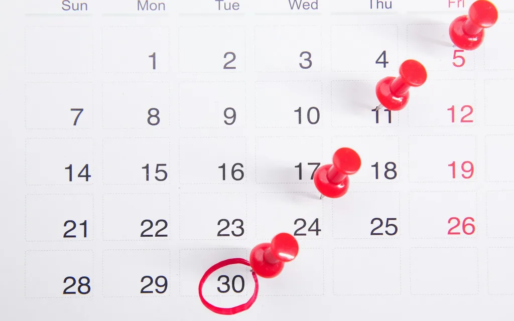 a calendar with red push buttons pinned to it